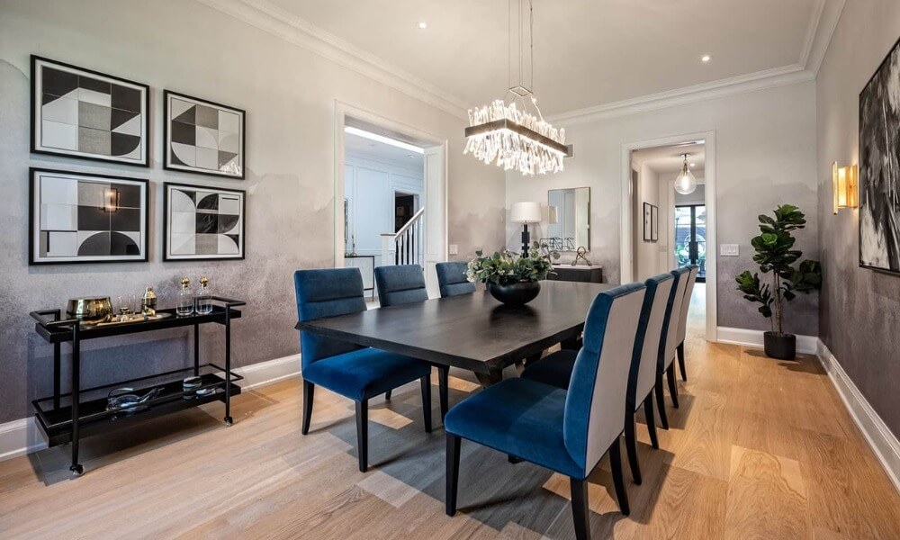 Phòng ăn sang trọng với bàn dài, ghế xanh và đèn chùm pha lê, trang trí nghệ thuật treo tường.