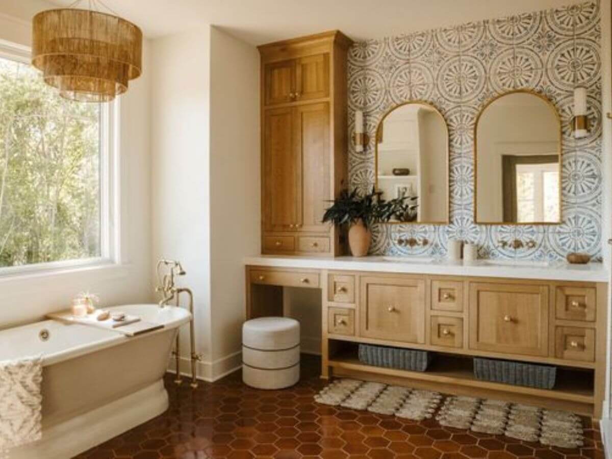 Phòng tắm phong cách bohemian với bồn tắm, gương đôi và ánh sáng tự nhiên qua cửa sổ lớn.