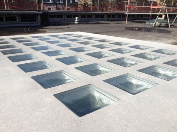 Mái nhà với ô kính vuông lắp đặt, ánh sáng tự nhiên chiếu qua, tạo cảnh quan hiện đại.