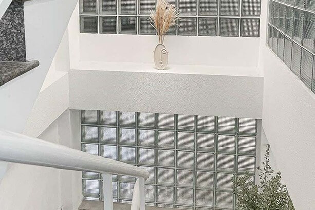 Cầu thang sáng tạo với tường kính, chậu cây trang trí hiện đại trong không gian nhà tối giản.