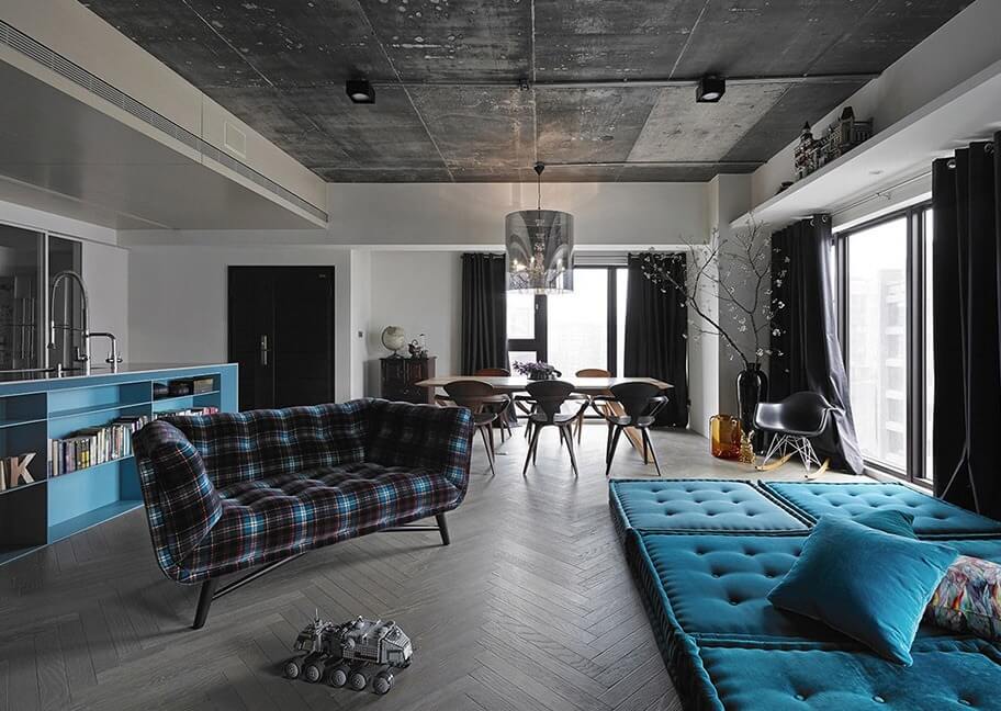 Phòng khách phong cách công nghiệp với sofa kẻ caro, ghế xanh dương, bàn ăn và cửa sổ lớn.