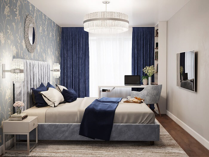 Phòng ngủ hiện đại, ánh sáng dịu, giường lớn, ghế sofa, đèn chùm, tranh treo tường và màn cửa màu xanh đậm.