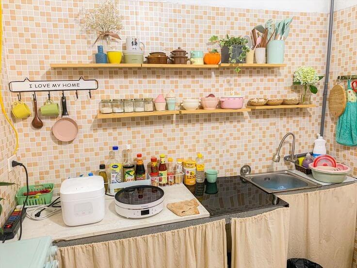 Nhà bếp nhỏ gọn với kệ để đồ, đồ gia dụng và bồn rửa, tạo không gian ấm cúng và tiện nghi.