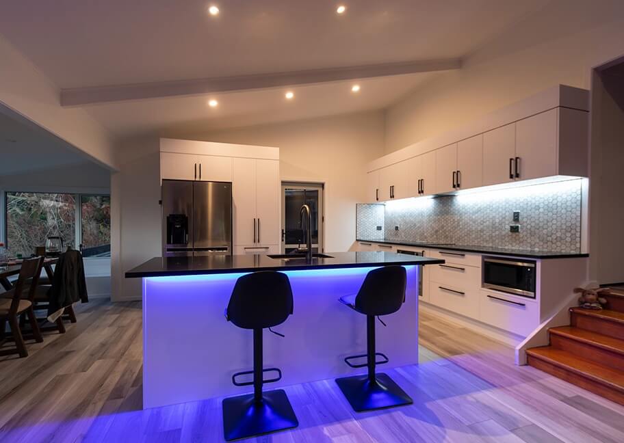 Nhà bếp hiện đại với đảo bếp ánh sáng xanh và ghế cao, tủ sáng tạo và không gian ăn uống.