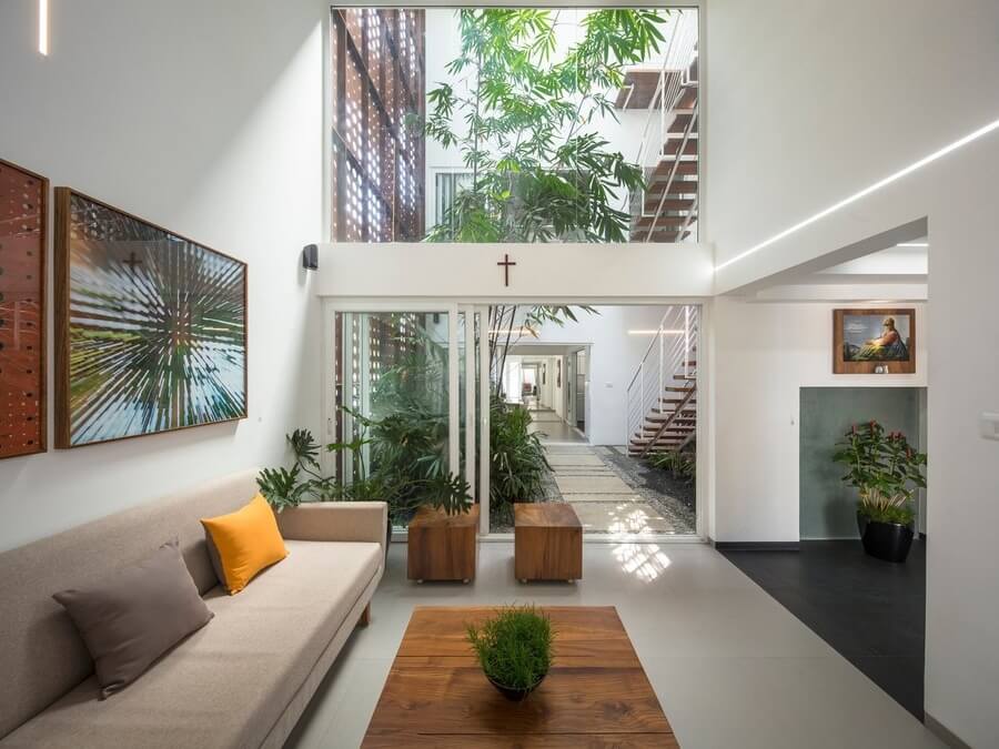 Phòng khách hiện đại với cửa sổ lớn, cây xanh, tranh treo tường và ghế sofa xám.