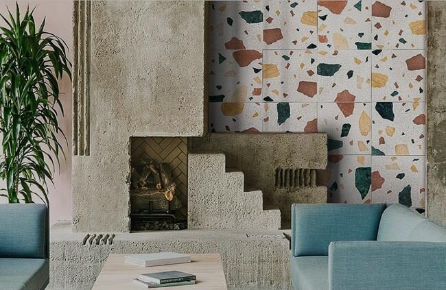 Phòng khách với tường terrazzo, ghế sofa xanh lơ và cây xanh, tạo nên không gian hiện đại và ấm cúng.