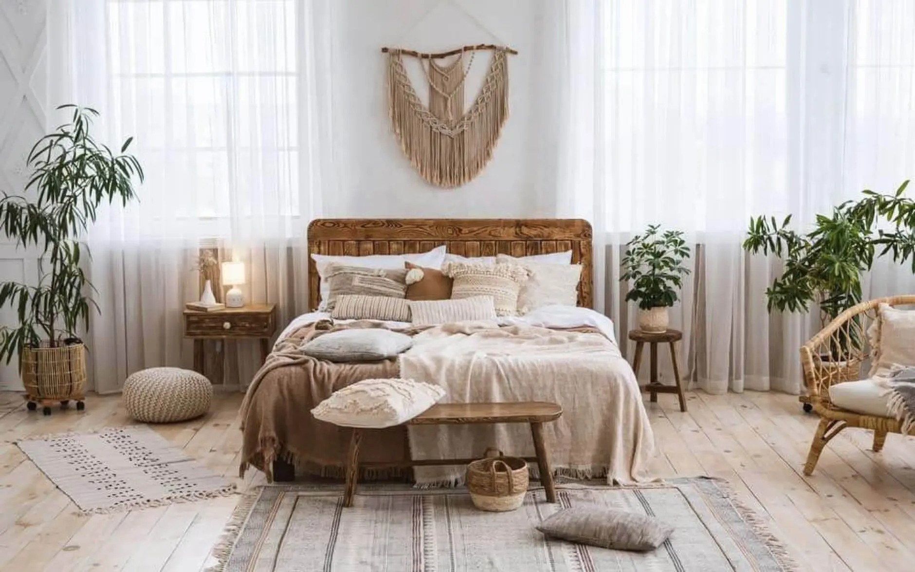 Phòng ngủ phong cách bohemian, nội thất gỗ, chăn gối màu trung tính, trang trí treo tường, cây xanh trong phòng.