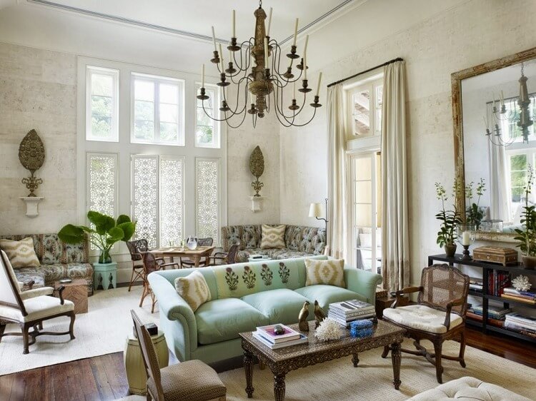 Phòng khách sang trọng với ghế sofa xanh nhạt, đèn chùm vintage, và cây cảnh tạo không gian thoải mái, ấm cúng.