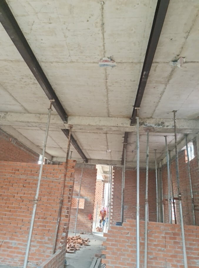 Công trình xây dựng với tường gạch đỏ và dầm thép tại Việt Nam.